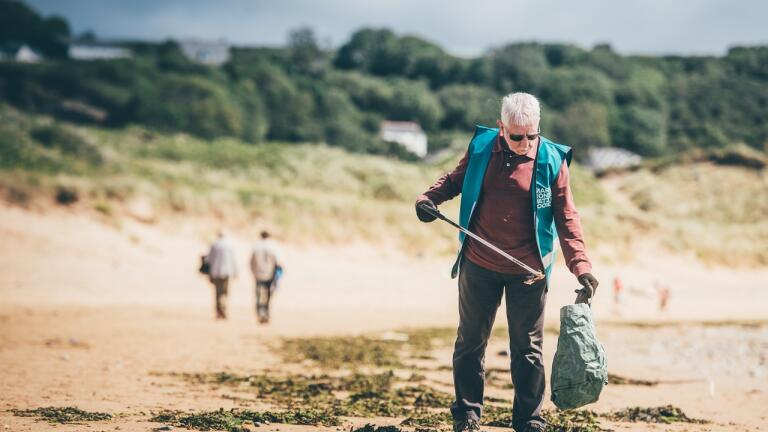 Ein Mann sammelt an einem Strand Müll