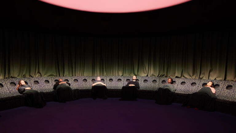 A group of people lying down on a circular seat.