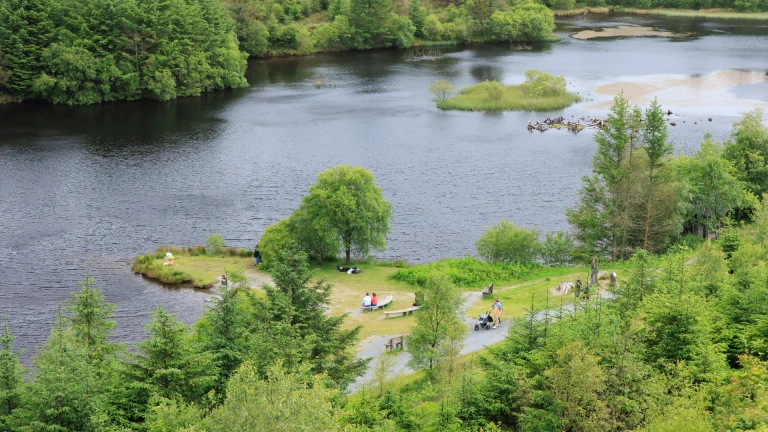 Aerial view of a lake with benches and wide gravelled pathways on the shore.