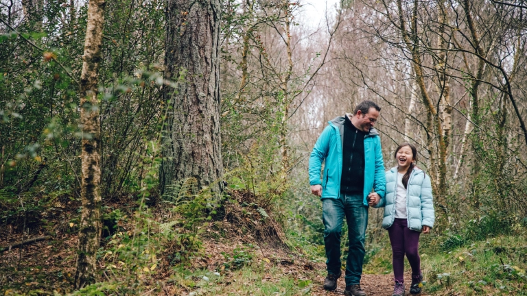 father and daughter walking in forest.