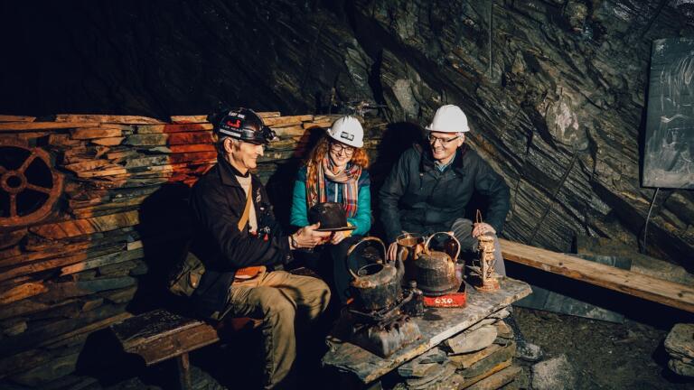 Three people wearing hard hats in an underground mine. 