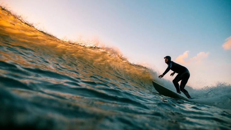 man on a surfboard riding a wave at dusk.
