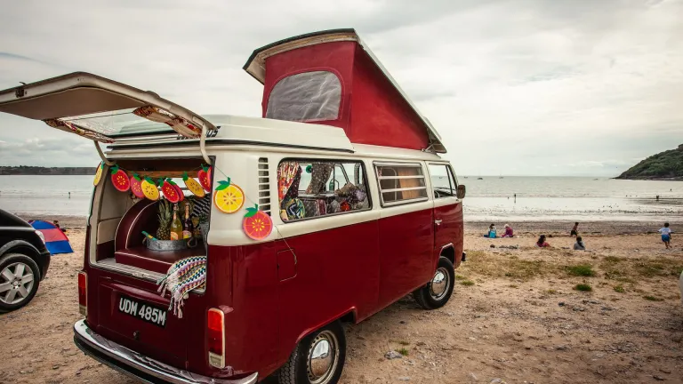 A VW campervan parked on a beach.