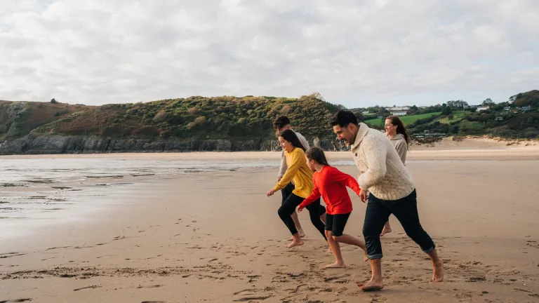 family running on sandy beach.