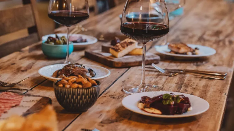 wooden table with tapas dishes and glasses of red wine.