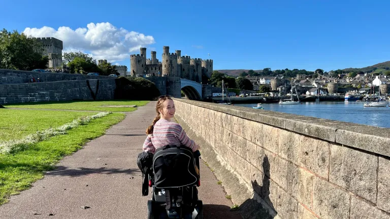 woman on motorised wheelchair with castle in background.
