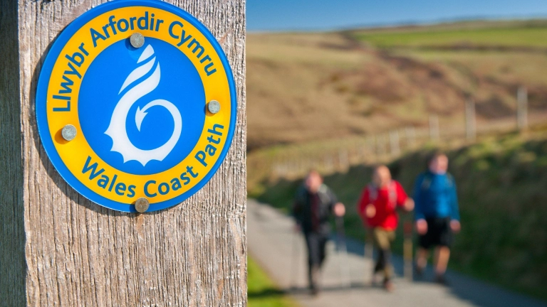 A sign on a post that says Wales Coast Path.