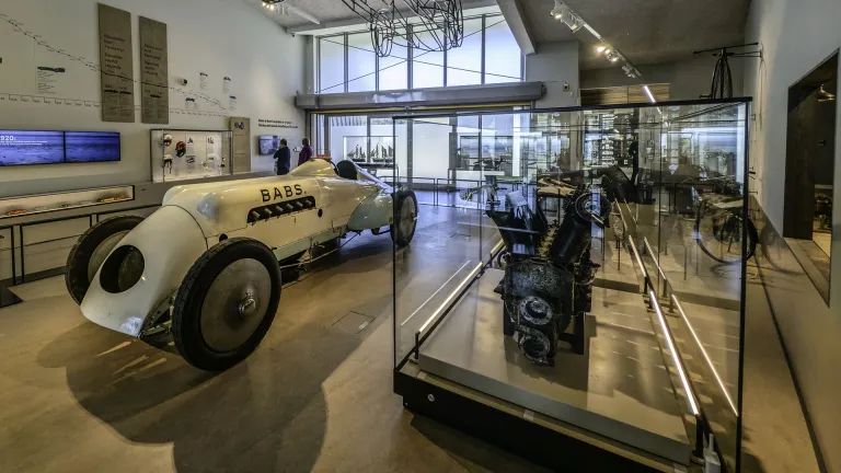 Interior of the Museum of Land Speed in Pendine, showing the historic 'Babs' racing car and engine displays in a bright gallery.