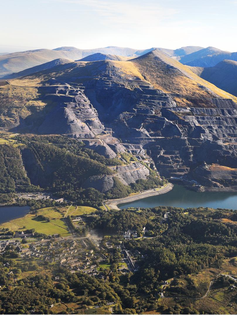 An aerial shot of a slate quarry with blue reservoirs below