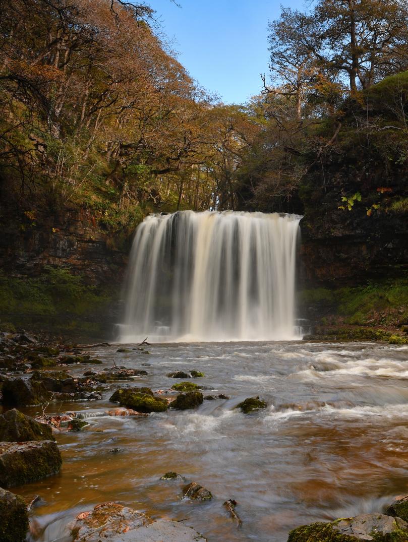 Sgwd yr Eira waterfall with trees in the background.