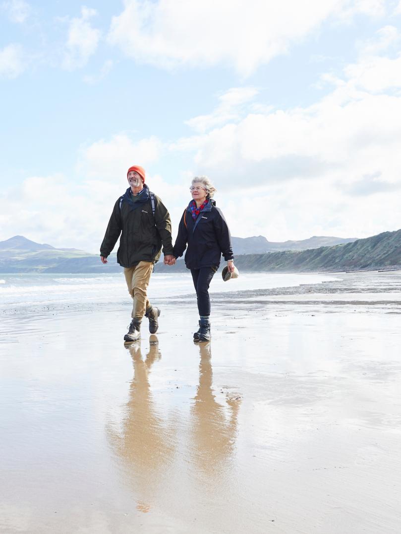 Couple walking on beach at Porthdinllaen.
