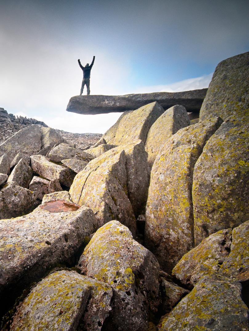 Wanderer, der die Hände in die Luft hält, auf dem Cantilever Rock, Snowdonia