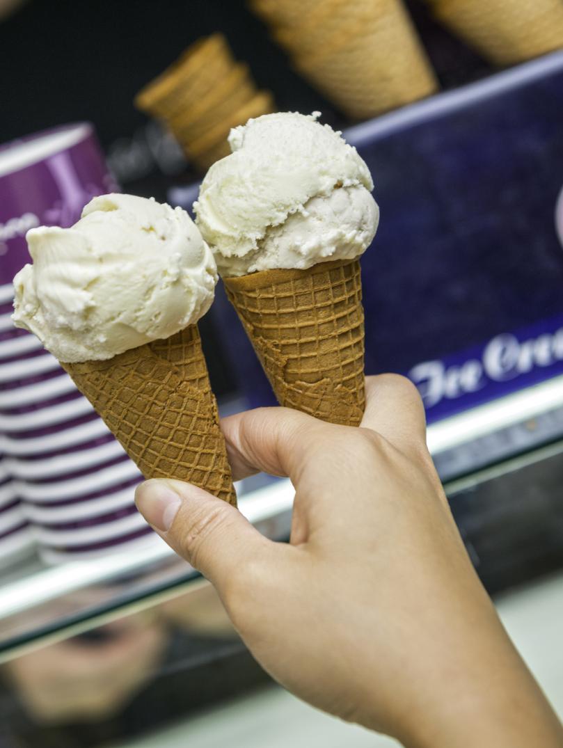 hand holding a couple of ice creams in cones.