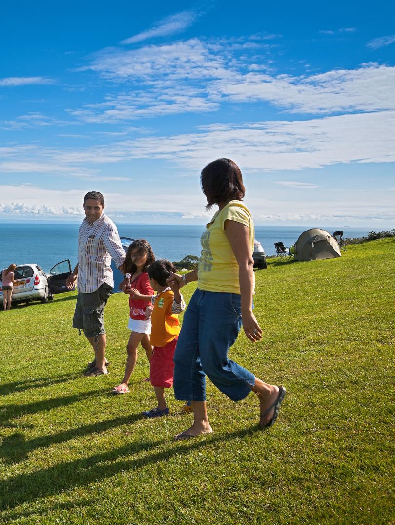Family (parents, son and daughter) playing at campsite overlooking beach.