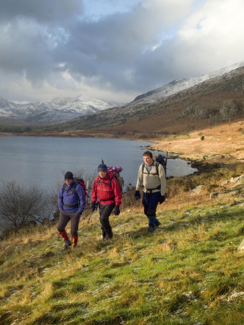 Drei Wanderer bei einem Spaziergang entlang des Sees Llynnau Mymbyr in Snowdonia.