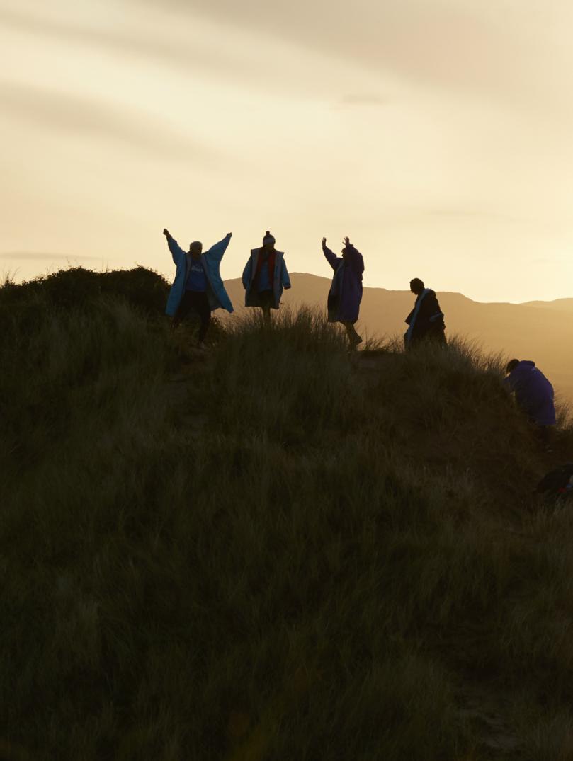 Five climbing a hill silhouetted against a sunrise