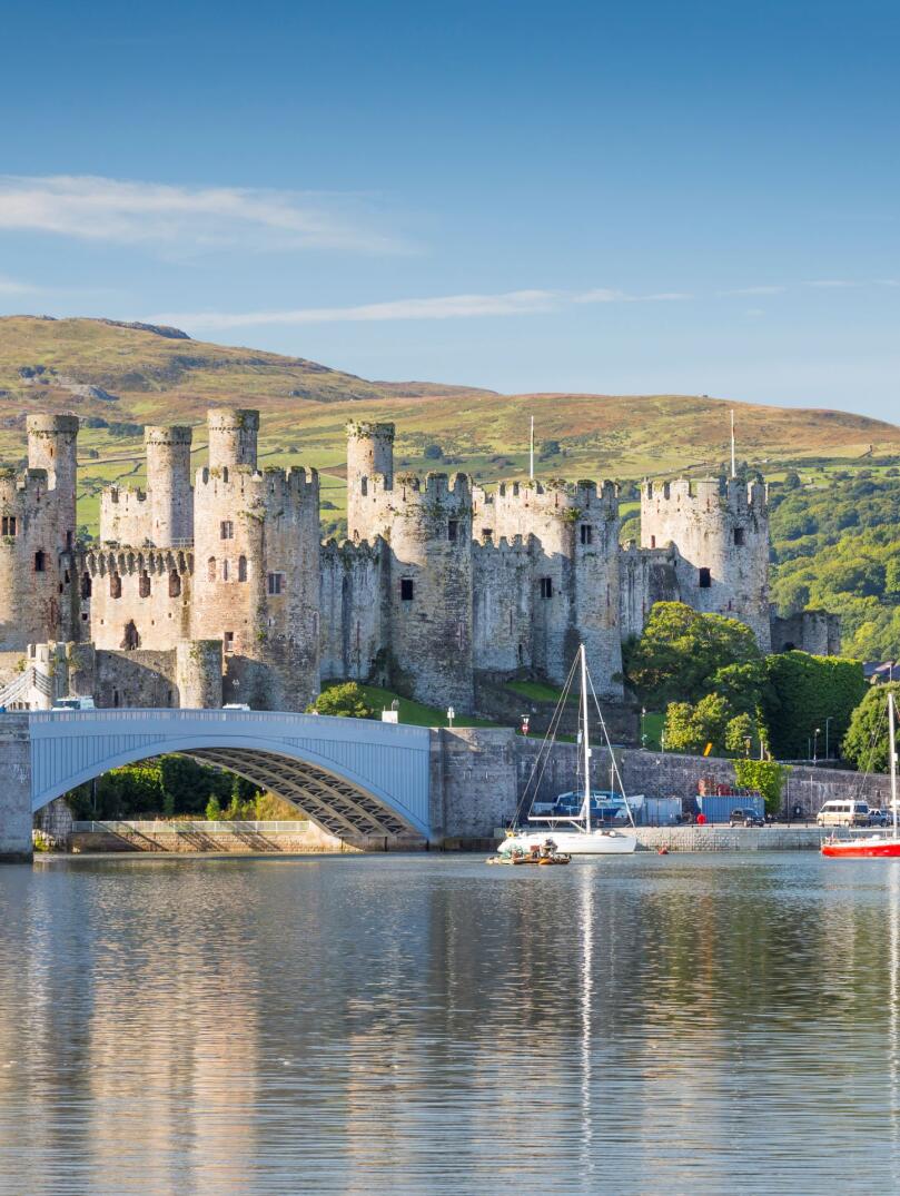 Looking across water to Conwy castle, with boats in the harbour.