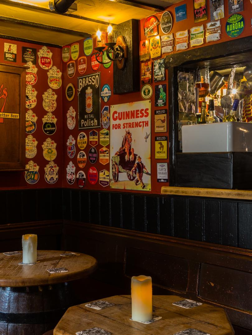 interior of old public house with walls decorated with beer mats and barrel tables.