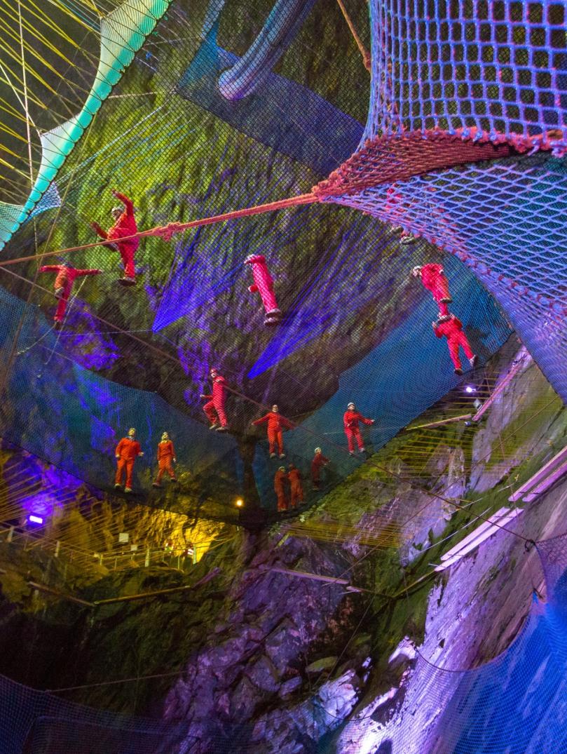 Group of people bouncing in a net in an underground cavern.