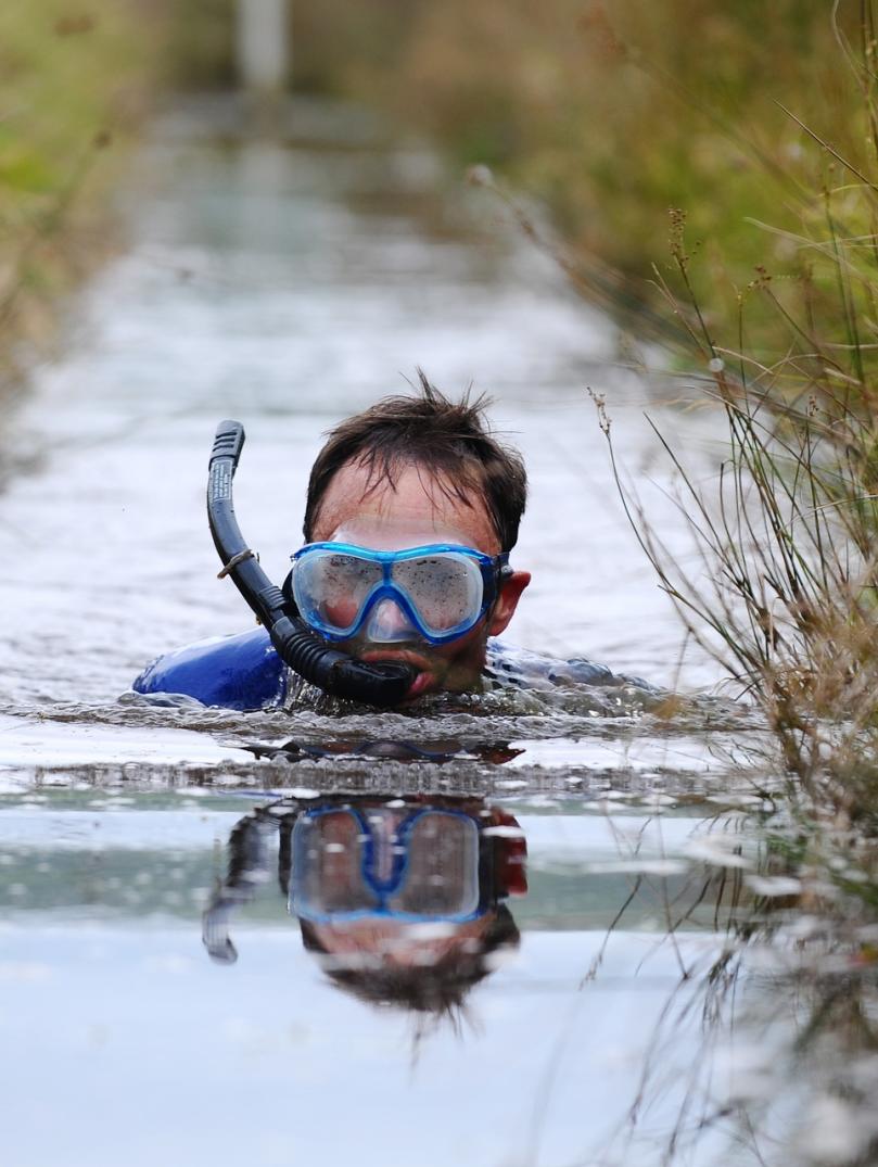 Image of a person wearing a snorkel and mask in a bog.