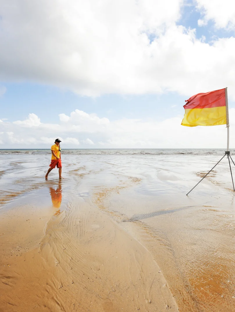 Two lifeguards walking across the beach