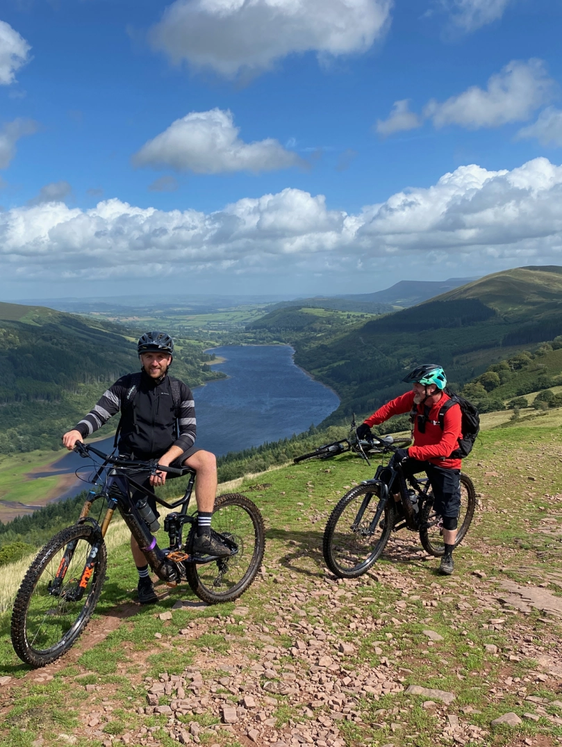 Zwei Personen auf Mountainbikes mit Blick über einen See.