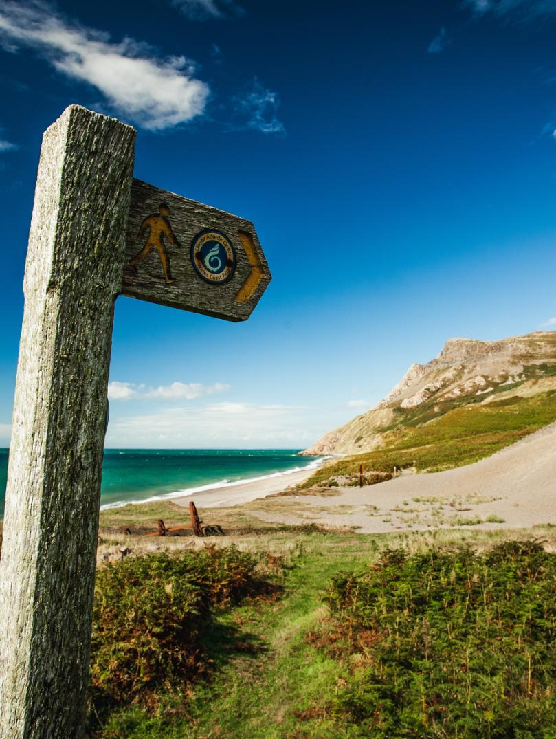 Wales coast path sign with sand dunes and sea in background