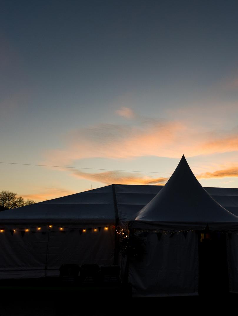 A tent with fair lights and a sunset in the background