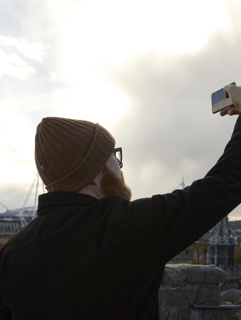 Ein Mann hält sein Handy in die Luft und macht ein Foto von Cardiff.