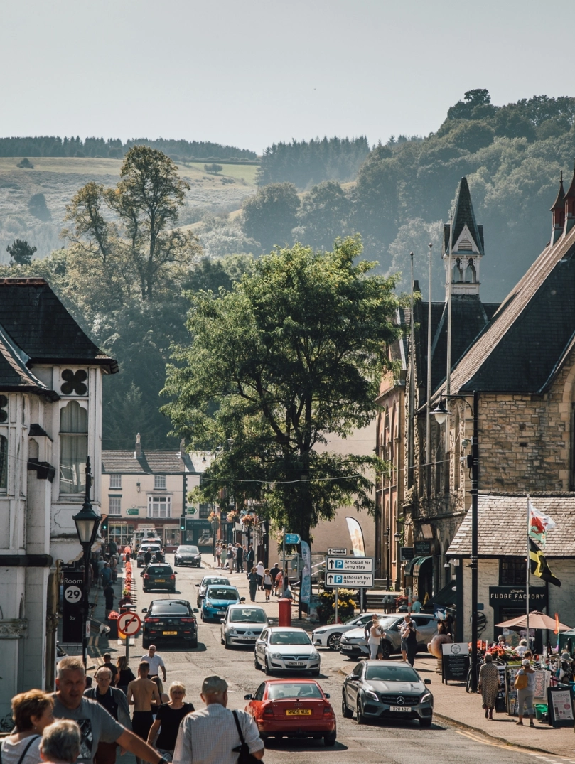 town with lots of people walking and cars plus countryside in background.