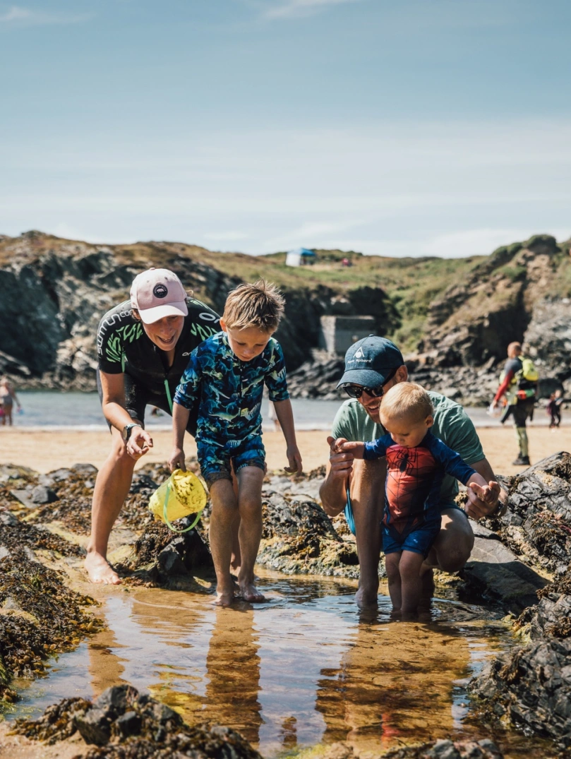 Four children exploring a rock pool on a beach.