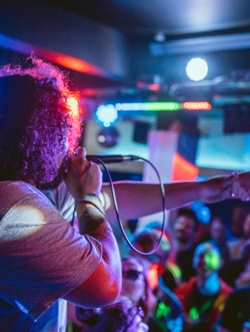 canwr ar y llwyfan a chynulleidfa yn y cefndir