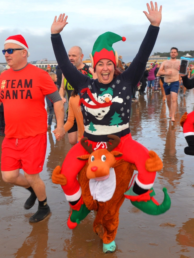 people in festive fancy dress on the beach.