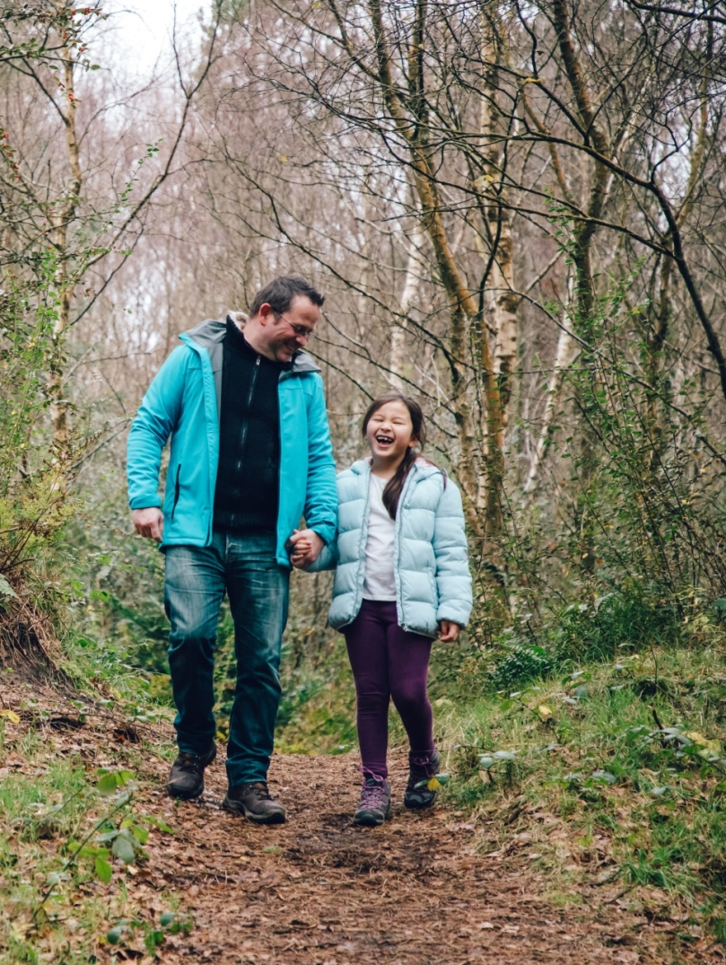 father and daughter walking in forest.