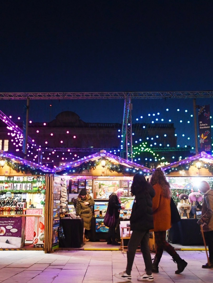 Marchnad Nadoligaidd gyda goleuadau llachar yn goleuo awyr dywyll.