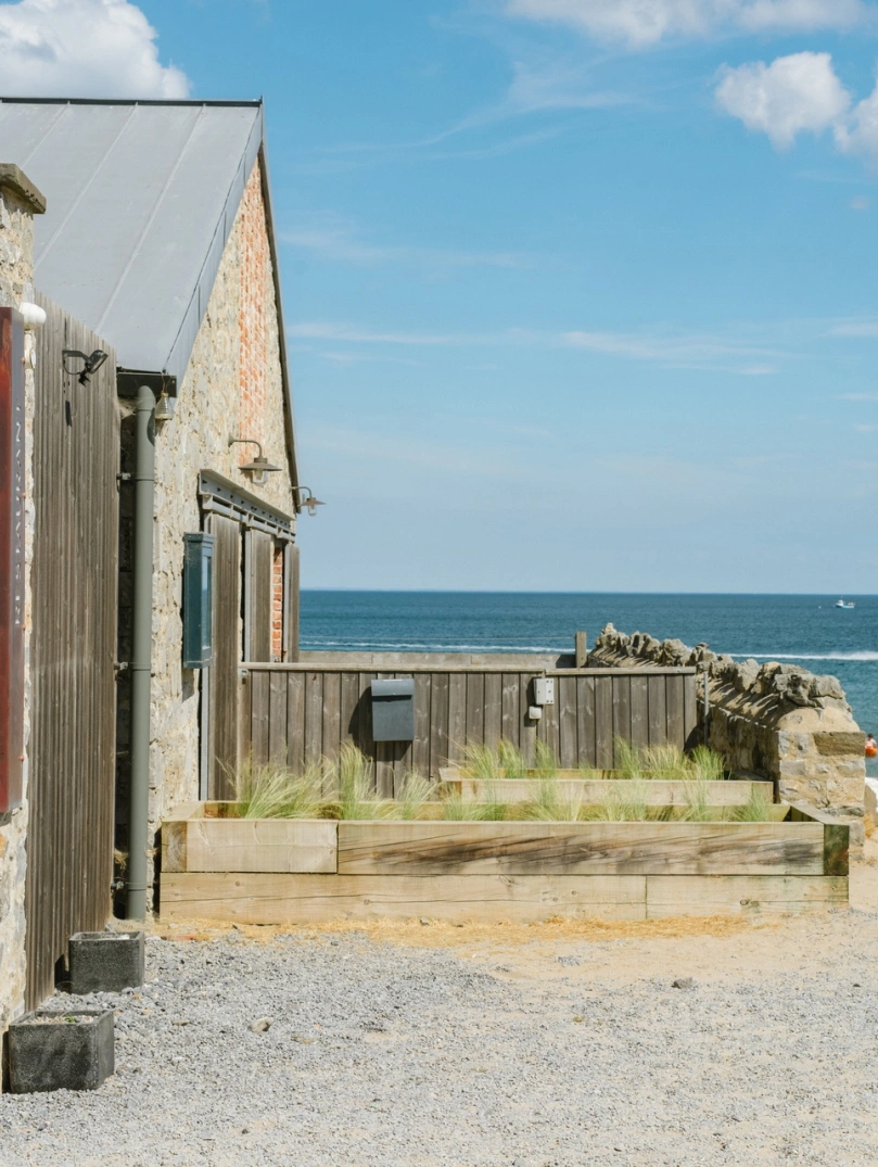 Tu allan bwyty Beach House yng Ngŵyr gyda'r môr yn y cefndir.