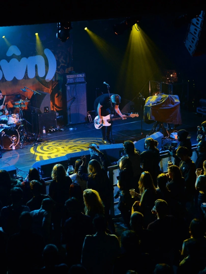 A band on a stage with a drummer and two guitarists.