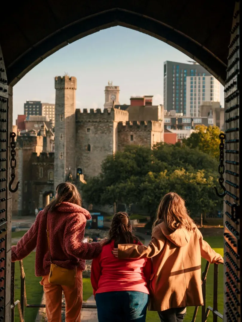 Grŵp o ffrindiau yn edrych allan ar y ddinas o ffenestr y castell 