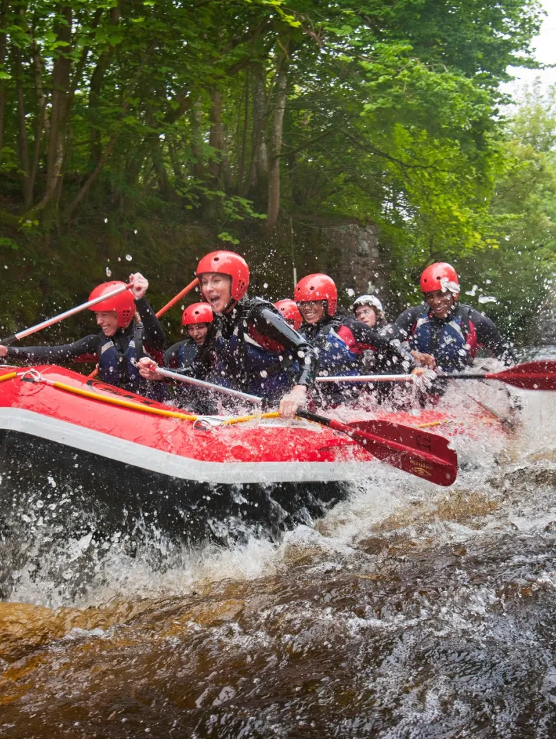 A group of people whitewater rafting down a river.