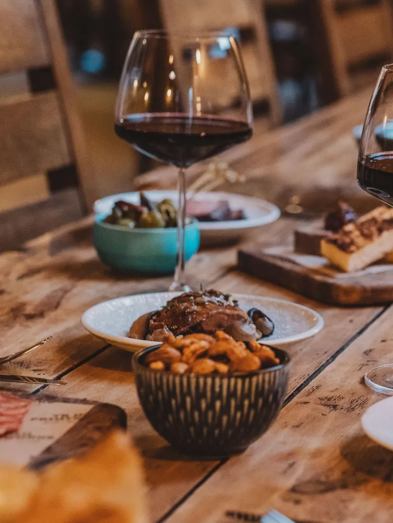 wooden table with tapas dishes and glasses of red wine.