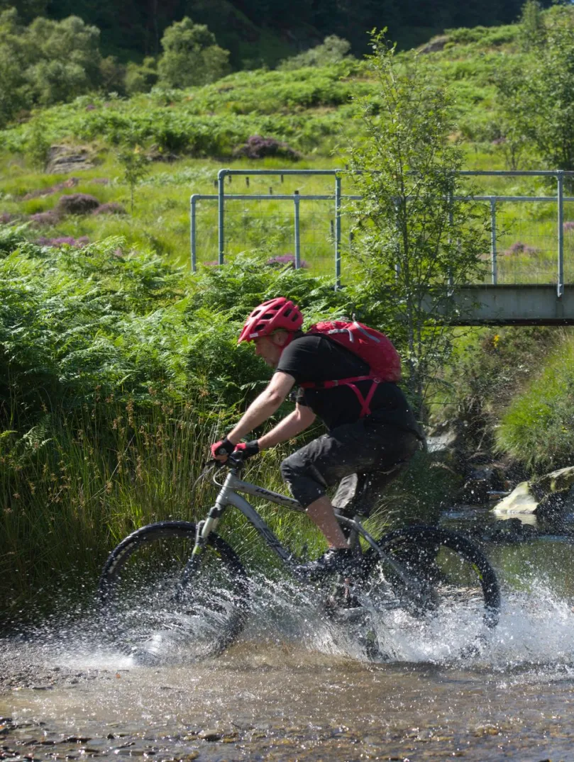 A mountain biker cutting through a river in Ceredigion. 