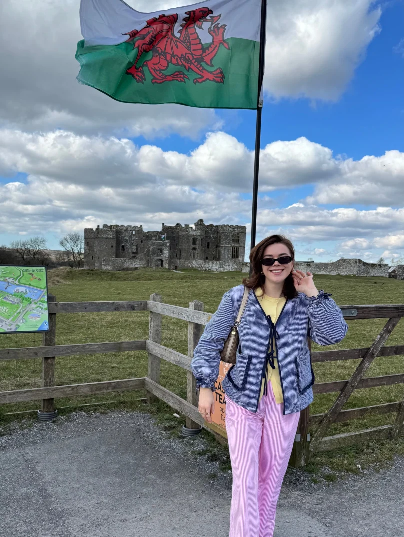 woman stood in front of Welsh flag with castle in background.