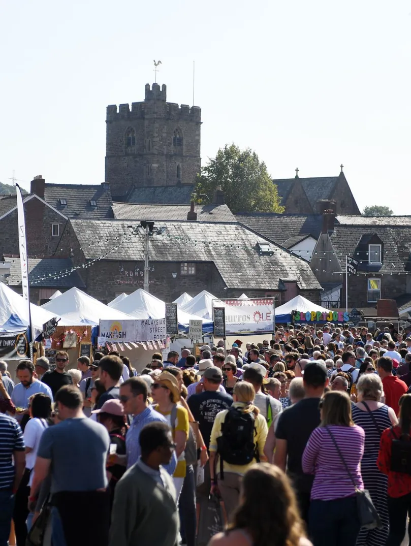 Crowds of people on a street enjoying a food stall filled food festival.