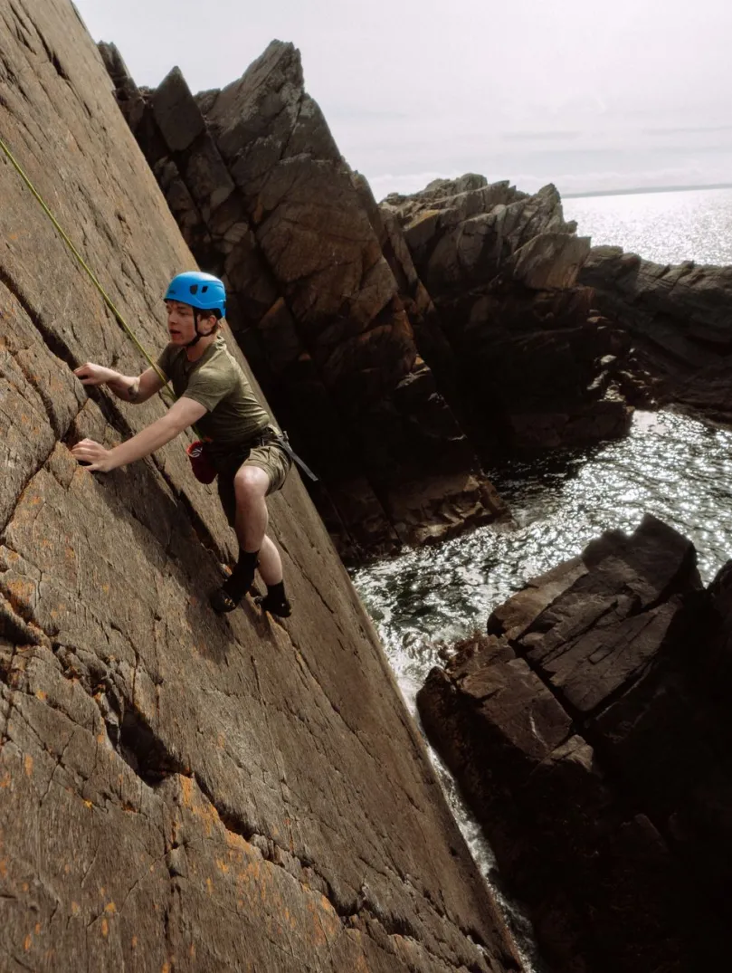 climbing wearing helmet climbing sea cliff.