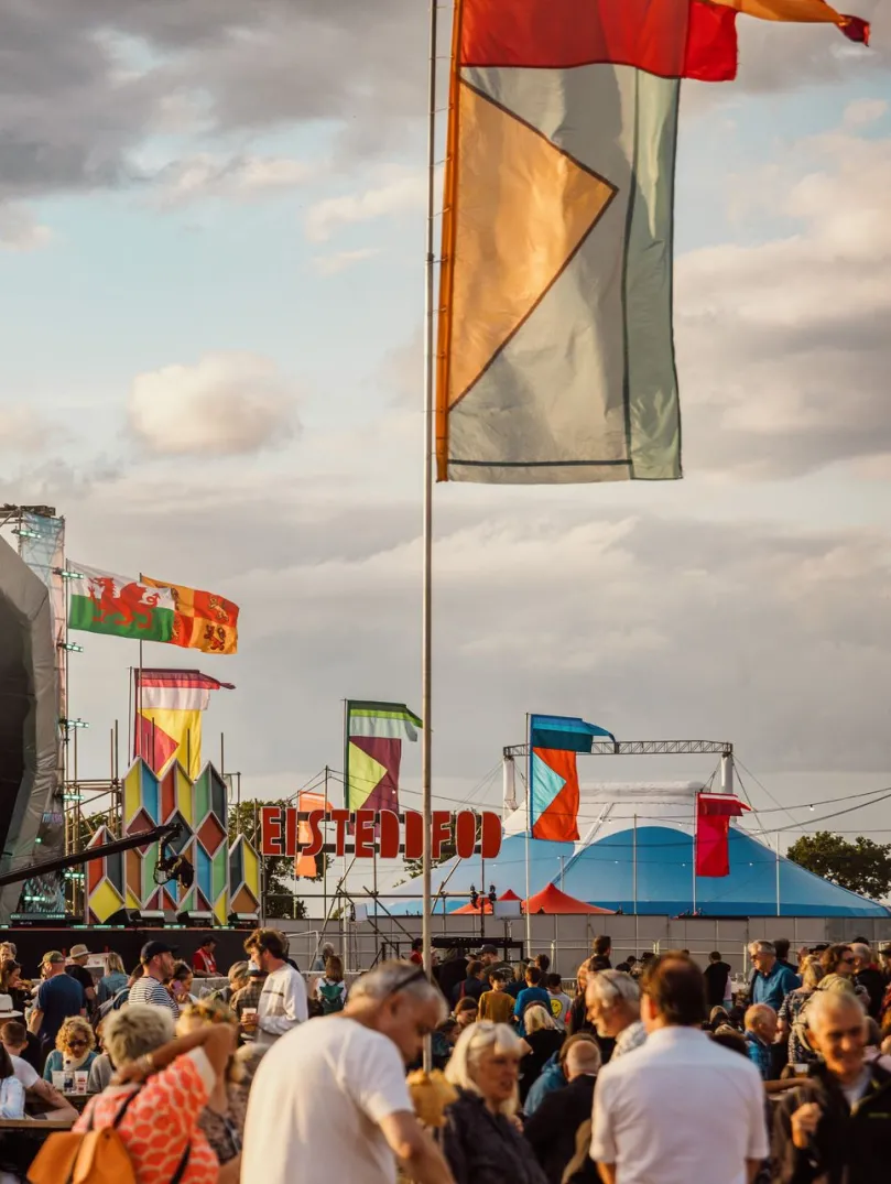 crowd enjoying Eisteddfod with stage and flags.