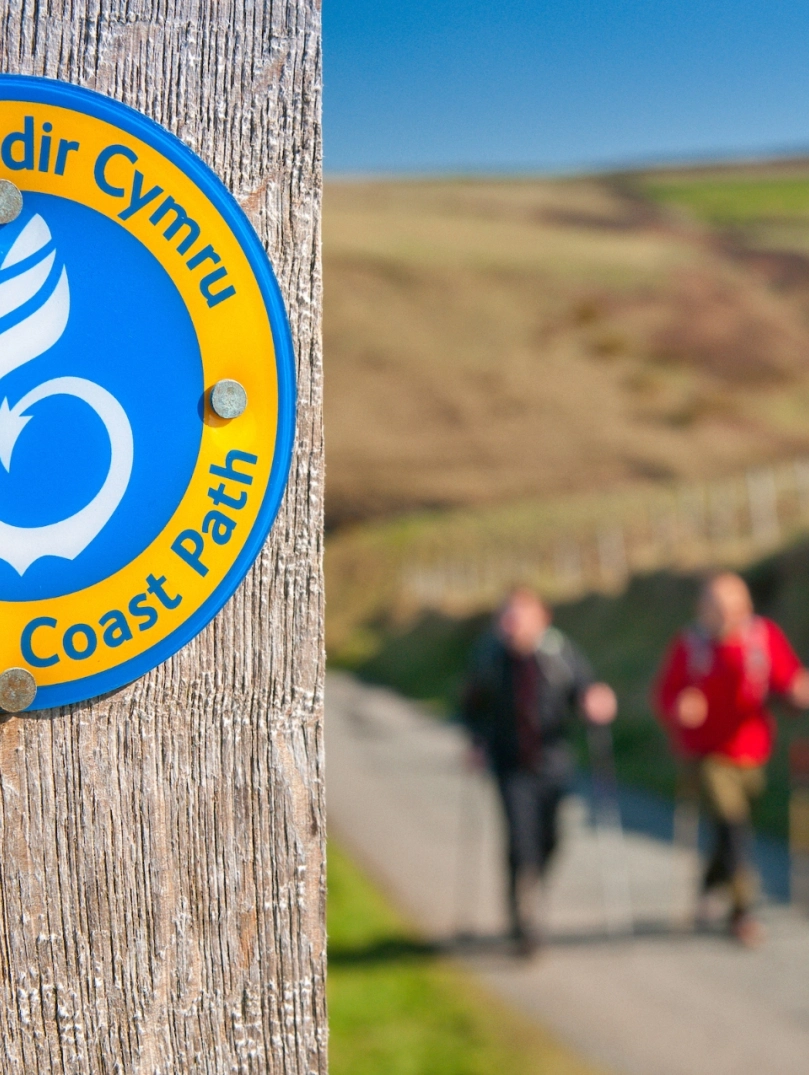A sign on a post that says Wales Coast Path.