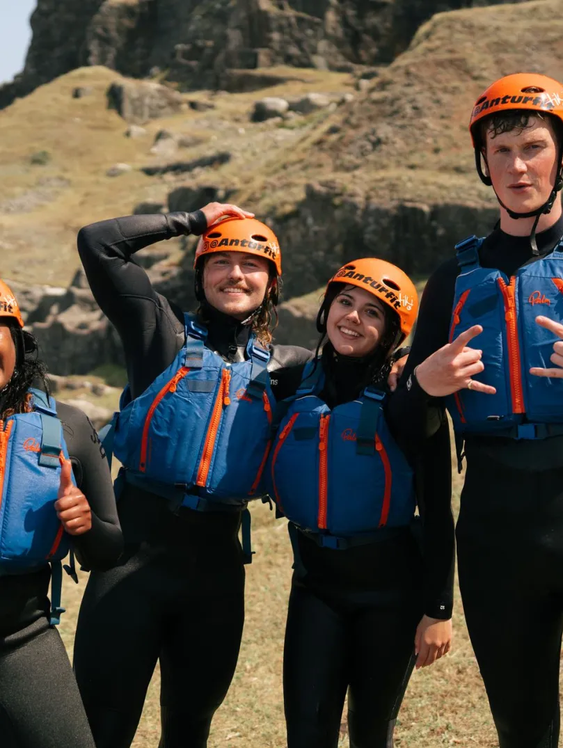 Four people in coasteering kit looking very happy. 