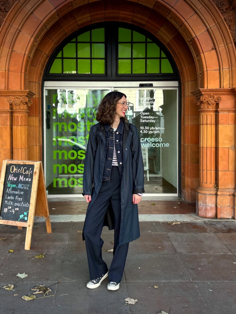 A woman standing outside the entrance to the art gallery which features ornate brickwork.