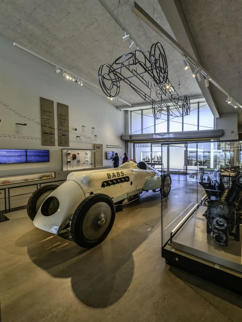 Interior of the Museum of Land Speed in Pendine, showing the historic 'Babs' racing car and engine displays in a bright gallery.