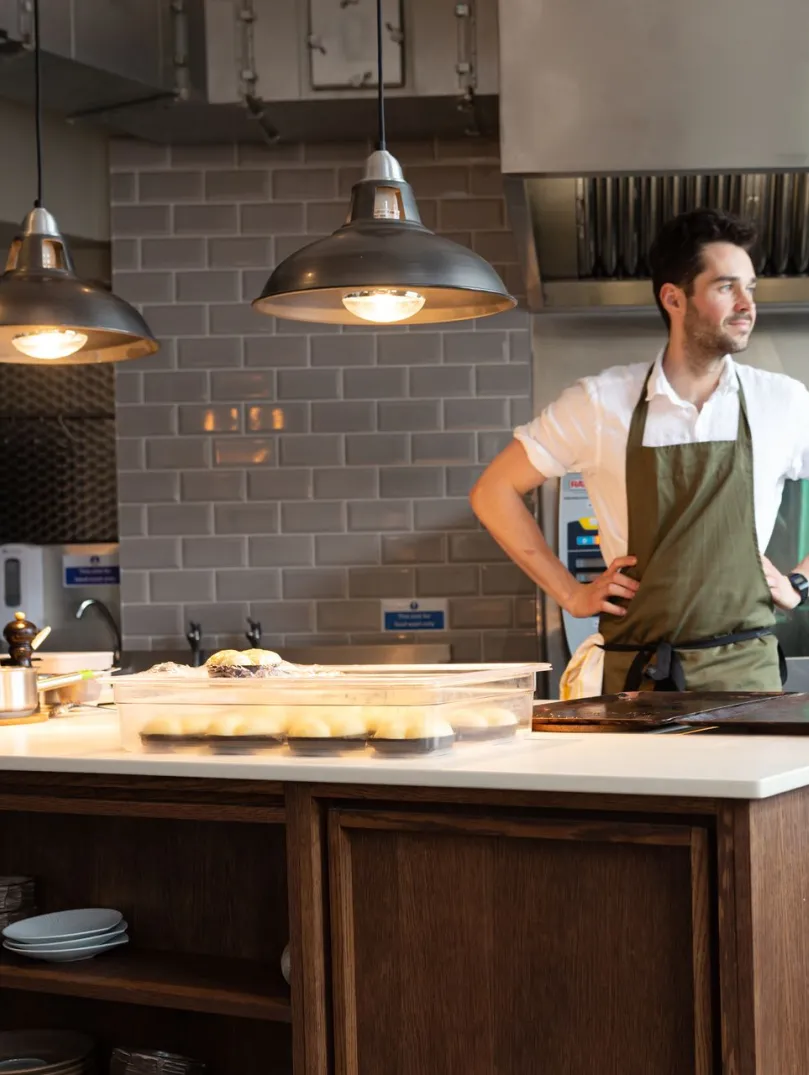Person preparing food at a kitchen island in a modern restaurant kitchen.